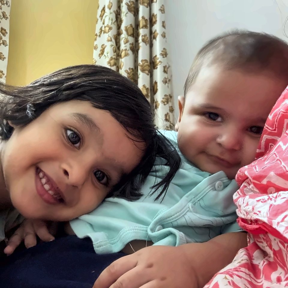 A smiling girl cuddling her baby brother