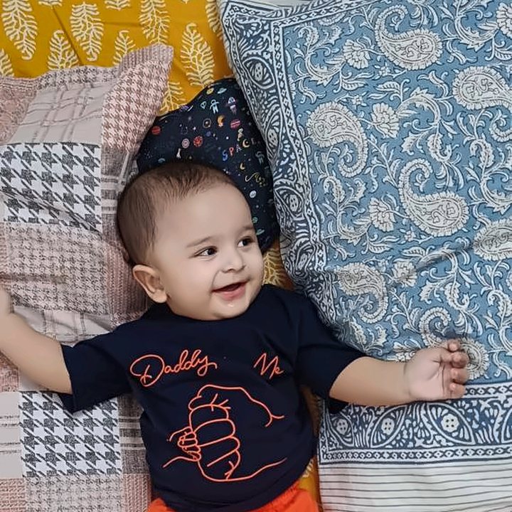 A happy baby lying on a patterned bedsheet